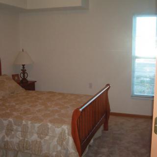 A simple bedroom with a wooden bed and a bedside lamp.