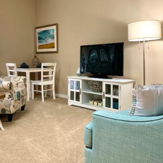 A cozy living room with a TV, sofa, and dining area.