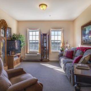 A cozy living room with comfortable seating, a television, and artwork on the walls.