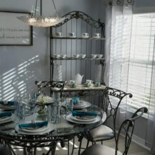 A cozy dining room with an elegantly set table, showcasing iron furniture bathed in natural light.
