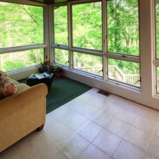 A bright sunroom with large windows offering a lush green nature view.