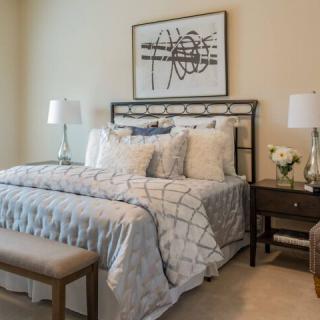 A cozy and elegantly designed bedroom featuring a well-dressed bed, stylish lamps, and artistic wall decor.