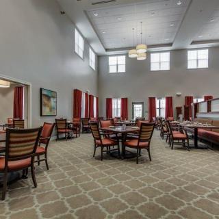 Spacious dining area with multiple tables, high ceilings, and large windows.