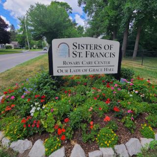 Entrance sign for the Sisters of St. Francis, surrounded by vibrant flowers.