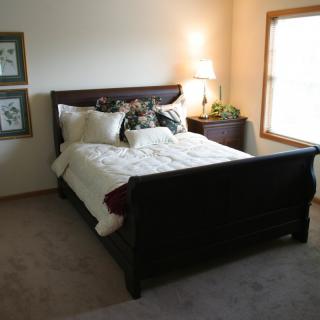 A cozy bedroom with a large bed and a bedside lamp illuminating the space.