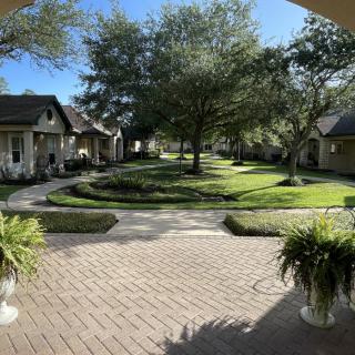 A tranquil courtyard with well-maintained gardens and surrounding houses on a sunny day.