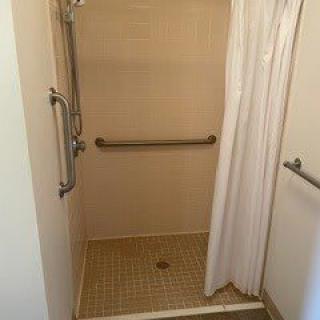 Accessible shower with grab bars and a curtain.