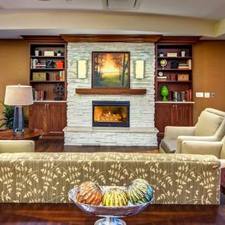 A cozy living room featuring a fireplace, flanked by bookshelves and armchairs, with a comfortable sofa and decorative elements.
