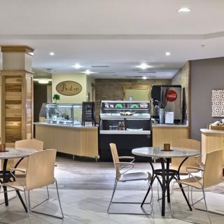 A cozy cafe interior with tables and chairs arranged around a display counter.