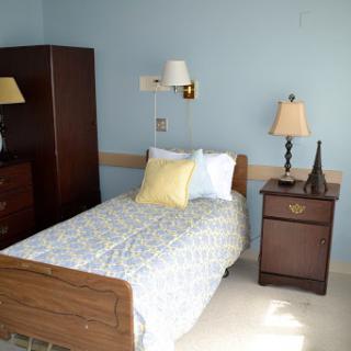 A cozy bedroom featuring a single bed, bedside lamp, and wardrobe.
