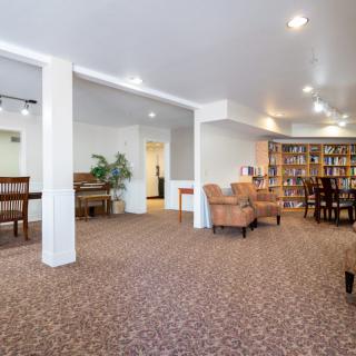A comfortable library with bookshelves, seating areas, and a carpeted floor.