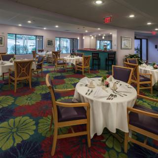 A cozy restaurant interior with neatly arranged tables and colorful carpet.