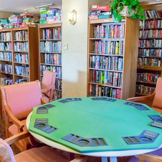 A cozy library space with bookshelves and a table set up for a card game.