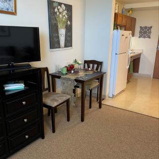A cozy apartment setup featuring a small dining area, TV, and view into the kitchen.