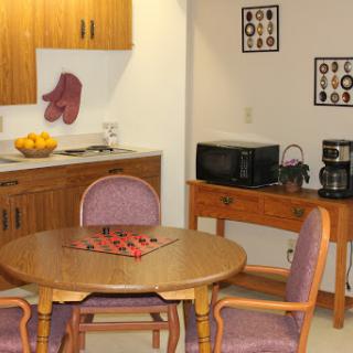 A cozy kitchen dining area featuring a round wooden table with chairs, a microwave, and a coffee maker.