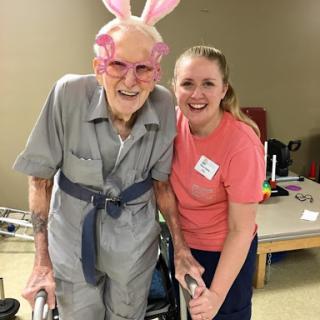 A joyful moment shared between an elderly resident and a caregiver, celebrating with bunny ears.