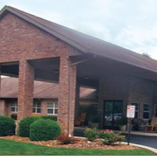A brick building with a covered entrance and landscaped surroundings.