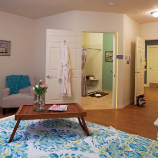 A cozy bedroom with a view into an adjoining bathroom, featuring comfortable furniture and inviting decor.