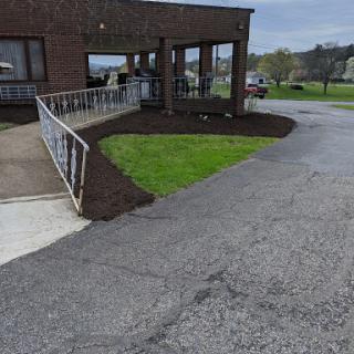 A landscaped area next to a building with a grassy patch and a winding pathway.