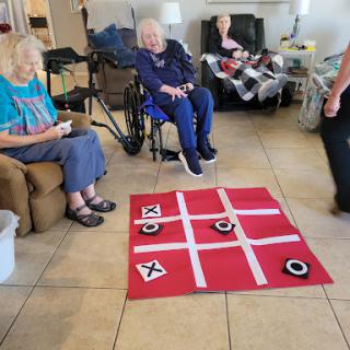 Elderly residents enjoying a game of tic-tac-toe in a community setting.