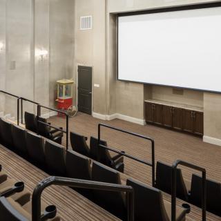 An empty theater room featuring a large screen and tiered seating.