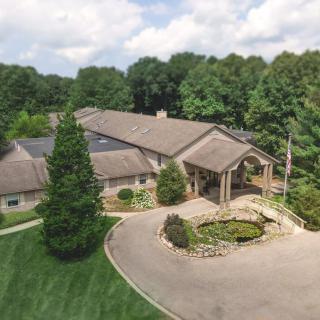 An aerial view of a large house surrounded by lush greenery and a circular driveway.