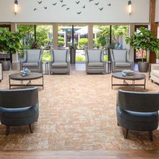 A spacious lobby with comfortable seating, filled with natural light and decorated with plants.