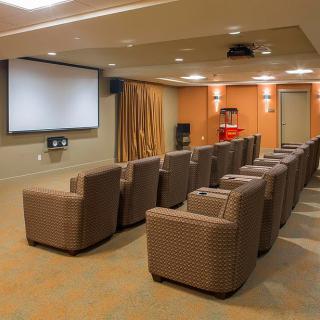 A cozy home theater room with comfortable seating and a large projection screen.