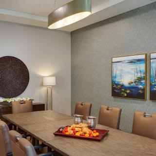 A modern dining room with a long conference table, stylish chairs, and artistic wall decorations.