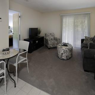 A cozy living room with comfortable seating, a TV, and a sliding door with blinds.