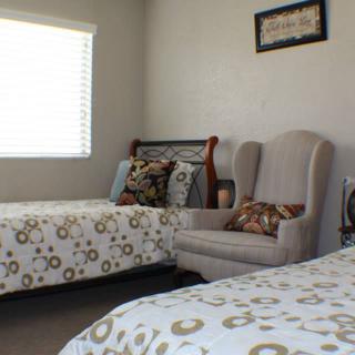 A cozy bedroom with two single beds, an armchair, and decorative pillows.