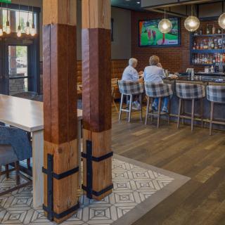 A cozy bar interior with wooden accents, seating, and a television.