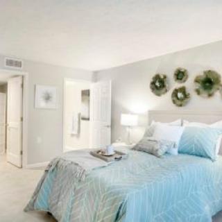A modern bedroom featuring pastel-colored bedding, decorative pillows, and simple wall art.