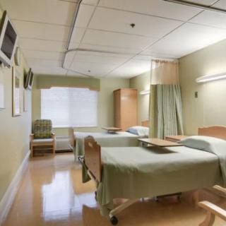 An empty hospital room with two patient beds and medical equipment.