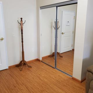An empty room with a wooden coat rack and mirrored closet doors.