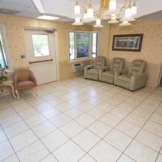 A waiting room with floor tiles, several chairs, and a window letting in natural light.