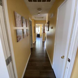 A well-lit hallway in a home, featuring wall art and multiple doors.