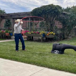 A cowboy practicing lasso skills in a garden.