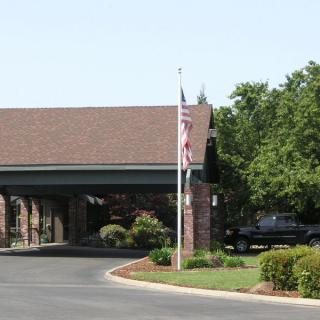 A building entrance with a flagpole and parked vehicle nearby.