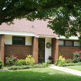 A charming brick house with a well-maintained garden and lush trees.
