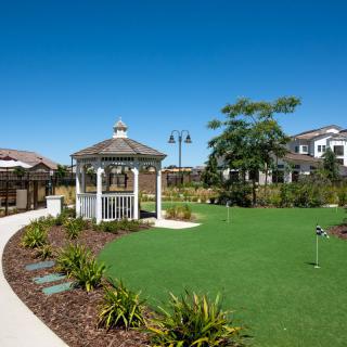 A well-maintained garden with a gazebo and landscaped pathways under a clear blue sky.