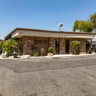 A small restaurant building with stone accents surrounded by plants on a sunny day.