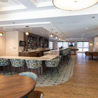 A modern bar and seating area with stylish decor and ample natural lighting.