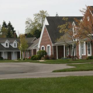 A quiet suburban neighborhood with well-maintained houses and greenery.