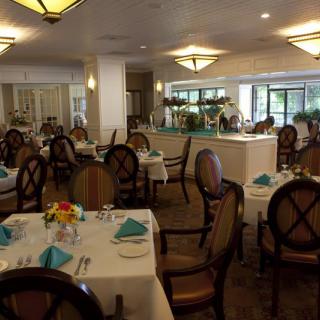 A formal restaurant dining room with elegantly set tables and chairs.