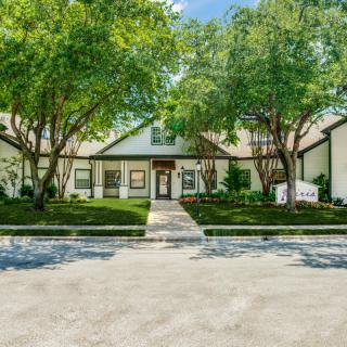 A modern residential home with a manicured lawn and surrounding trees.