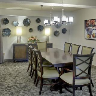 A stylish dining room featuring a long table with chairs, modern lighting, and decorative wall art.