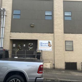 A view of a commercial building with a prominent sign, accompanied by a parked silver vehicle.