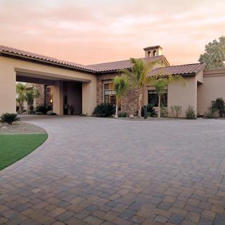 A beautiful house with a spacious driveway and palm trees at sunset.