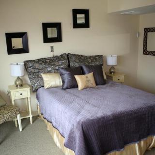 A cozy bedroom with elegant decor, featuring a bed adorned with pillows and flanked by bedside lamps.